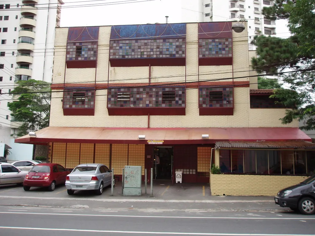 Fachada de padaria de dois andares na Rua Vieira de Morais, com toldo vermelho e carros estacionados em frente